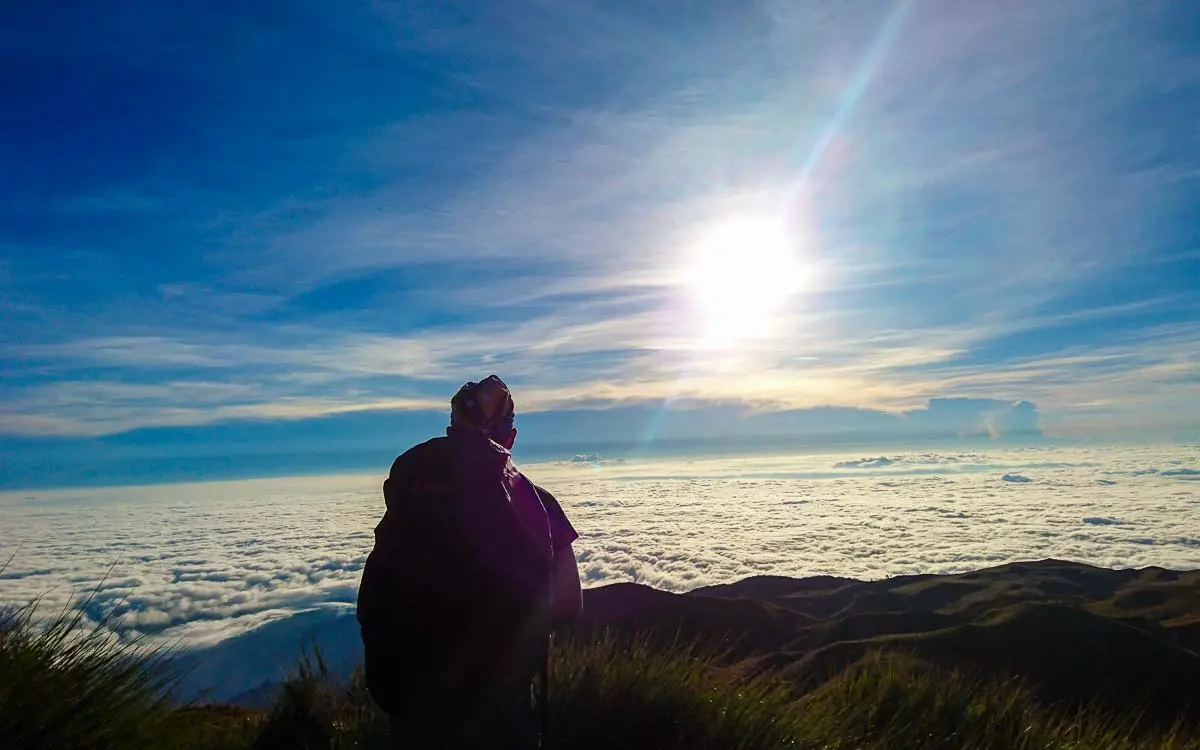 Hiker watching the sea of clouds sunrise at Mount Pulag summit