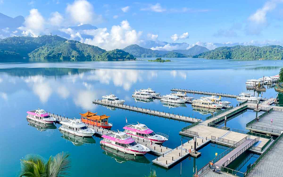 Tourist ferry boat cruising across Sun Moon Lake with mountain scenery in background