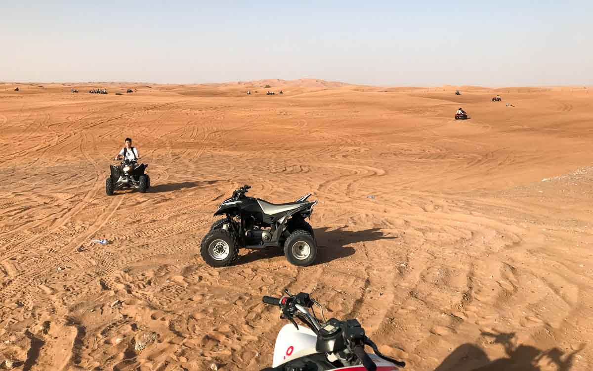 Tourist riding quad bike on golden sand dunes during Dubai desert safari