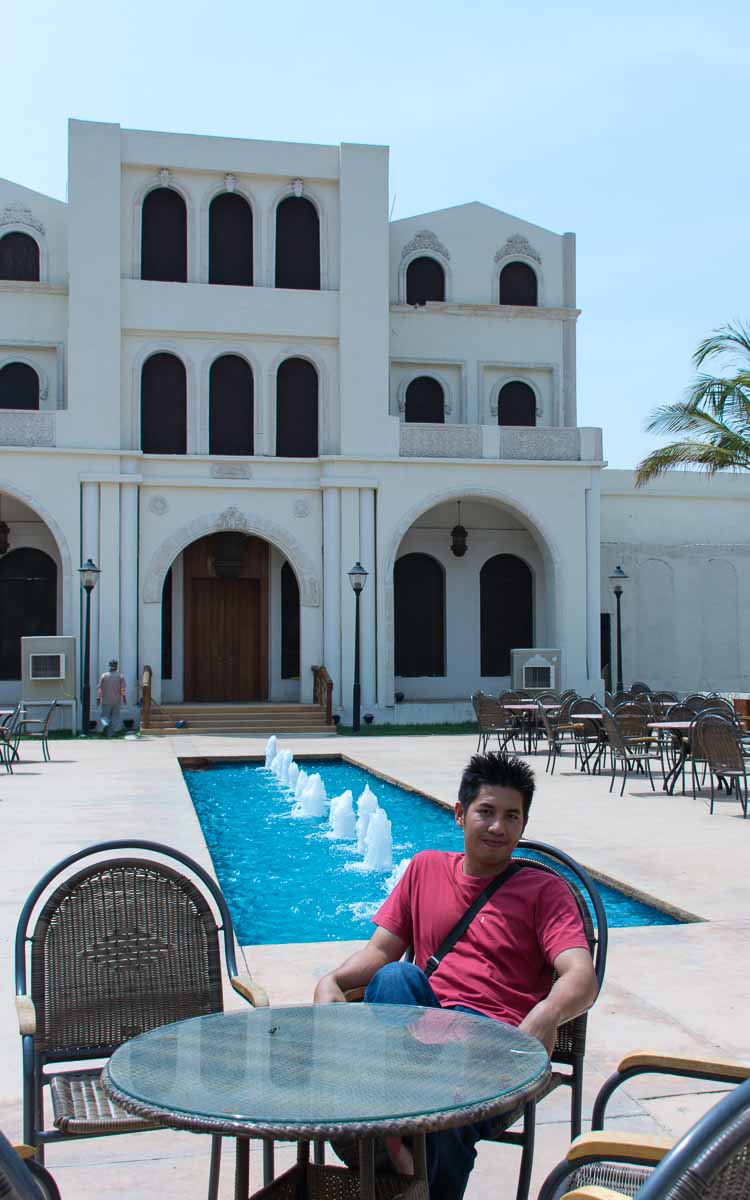 A man wearing a red shirt sitting in a chair inside the Al Kar Tourist Village