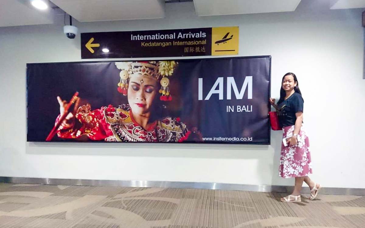 A woman next to a signboard inside Bali Airport