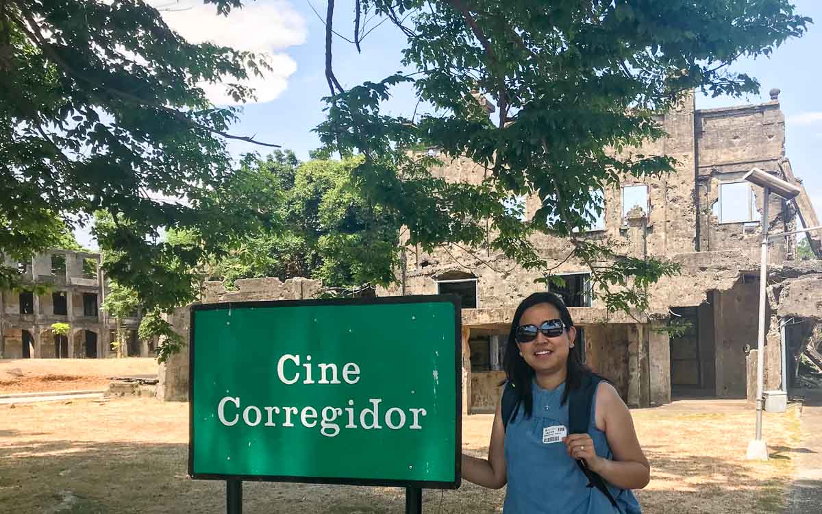 a woman in blue skirt beside the sign board of Cine Corregidor