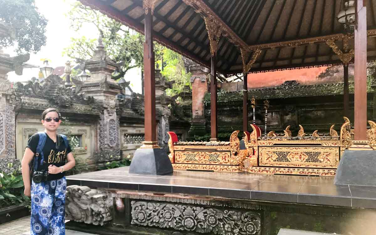 A woman in a black shirt carrying a camera at Ubud Palace