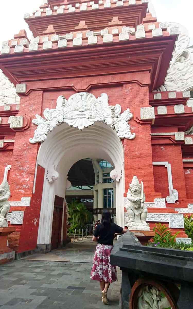 A woman in a black shirt in front of the gate at Bali Airport