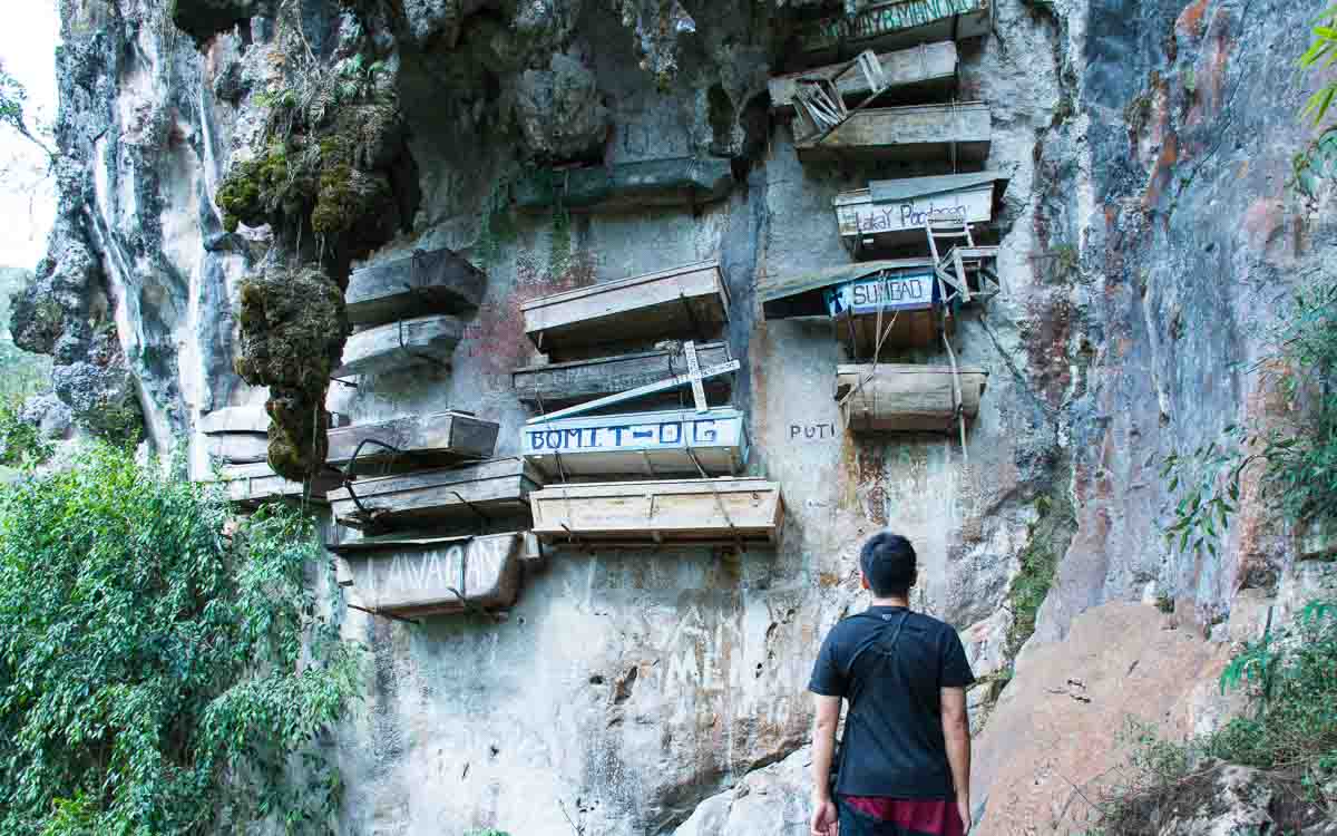 A man in a black shirt observing the Hanging Coffins in Sagada