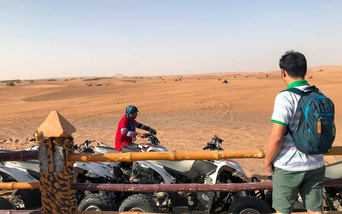 A man observing a quad bike rider in the desert safari