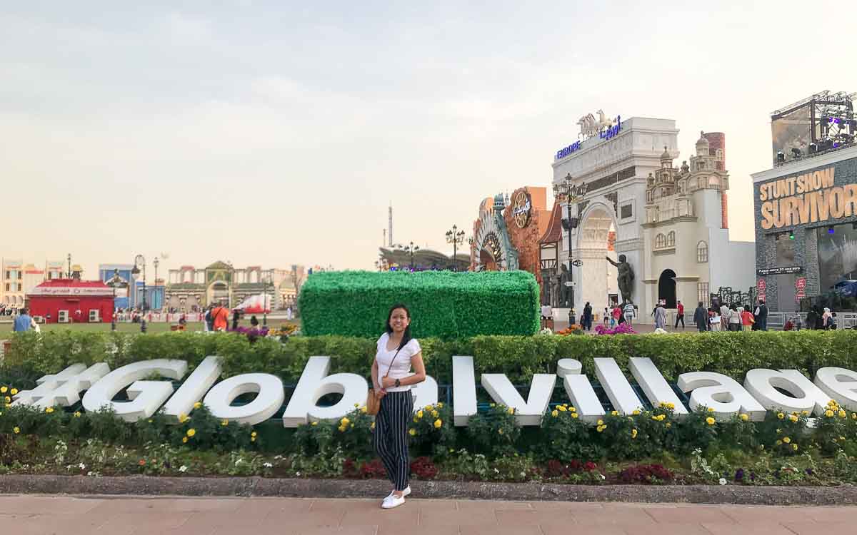 A woman standing in front of the hashtag sign of Global Village.