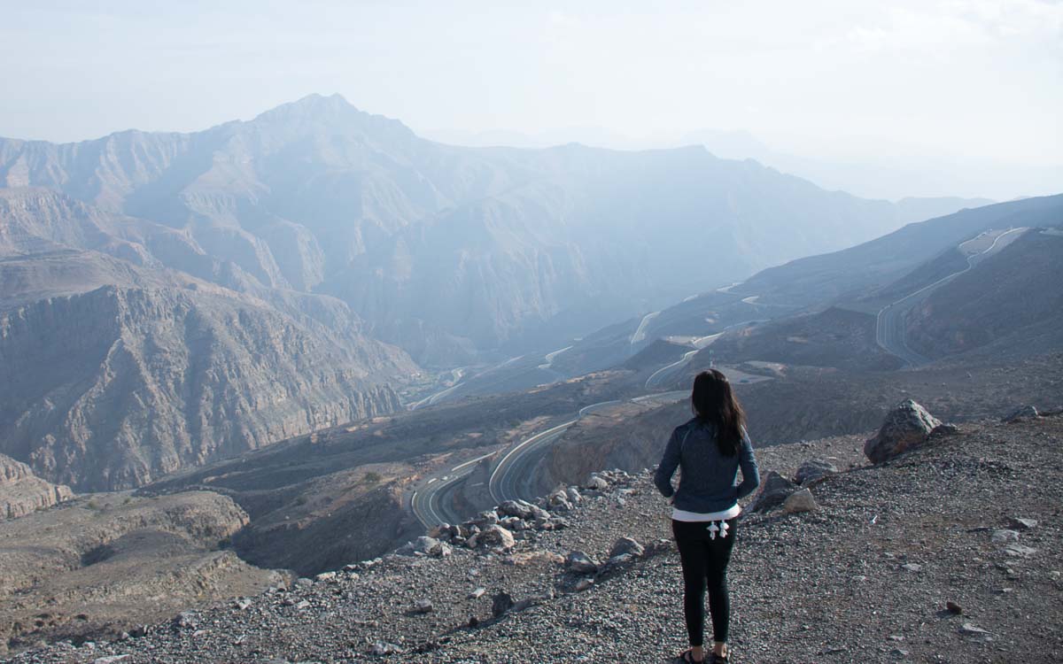 Tourist standing at Jebel Jais summit viewing deck with mountain panorama in Ras Al Khaimah