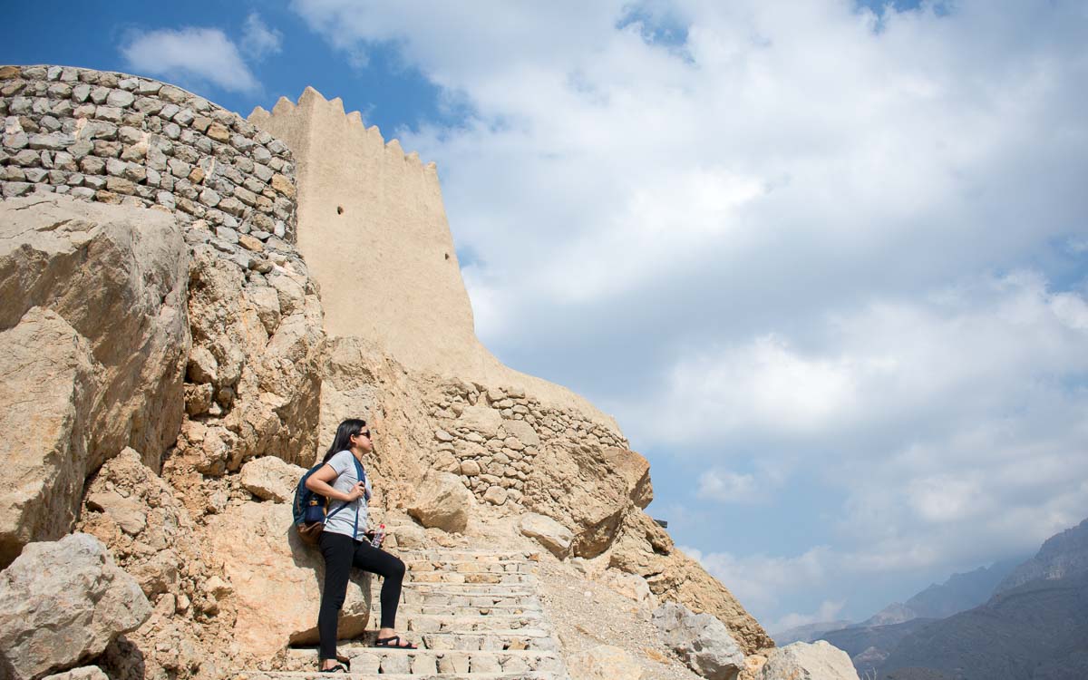 a woman standing on a stone staircase at Dhayah Fort