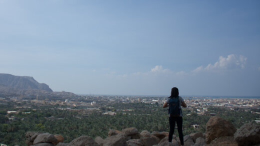 a person standing on rock ledge looking at a city