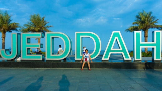 a man sitting infront of Jeddah sign at Corniche Waterfront