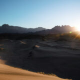 Solo traveler walking through a vast desert landscape in Saudi Arabia, part of an epic adventure in the Middle East.