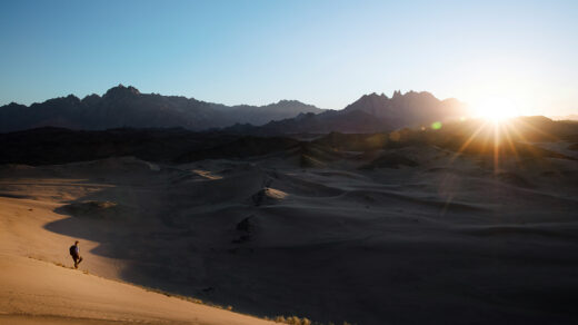 Solo traveler walking through a vast desert landscape in Saudi Arabia, part of an epic adventure in the Middle East.