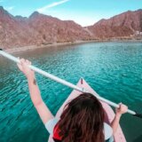 Tourist kayaking on turquoise waters of Hatta Dam surrounded by dramatic Hajar Mountains in UAE