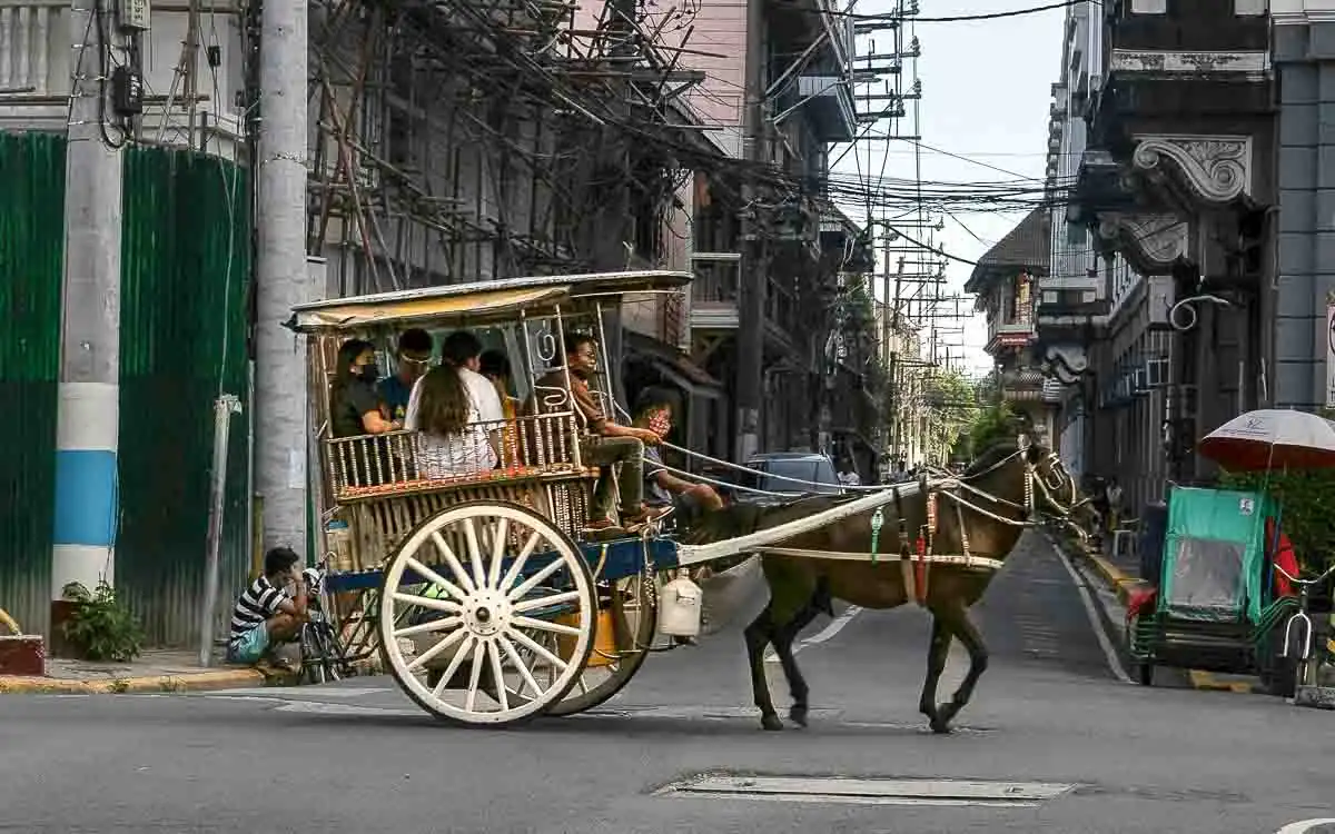 A traditional kalesa horse-drawn carriage traveling through the historic streets of Intramuros, Manila.