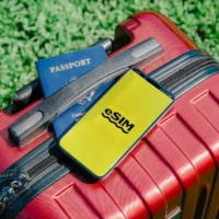 Close-up of a red suitcase with a smartphone displaying eSIM and a passport, representing travel preparation for Saudi Arabia