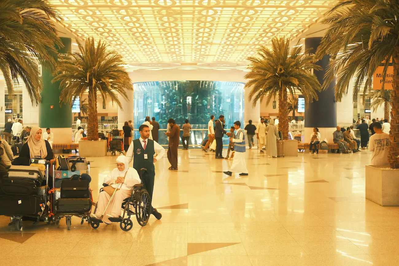 Travelers moving through a busy airport terminal with palm trees